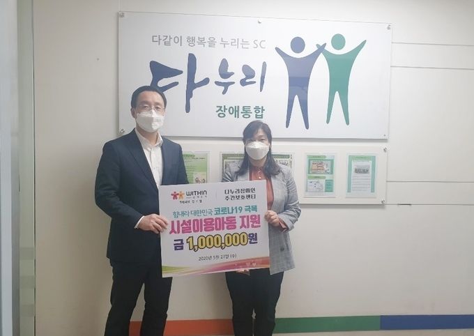 정기열 (사)위드인 사람과함께 후원회장이 27일 시설이동아동 지원금(100만원)을 안양 다누리 장애인시설 백승미 시설장에게 전달하고 있다.