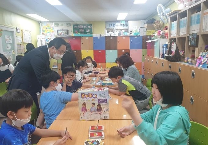정기열 후원회장이 27일 시흥 큰별 지역아동센터를 방문해 지원금을 전달하고 시설이용 아동들과 눈높이를 맞추고 있다. 