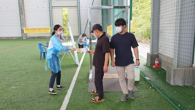 임시총회 행사장 출입구에 설치된 소독제 및 에어 소독 부스를 통과하는 수용주민들