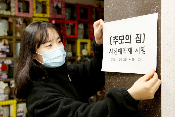 28일 오전 공사 관계자가 추모의 집에 사전예약제 안내문을 부착하고 있다. / 사진=수원도시공사 제공