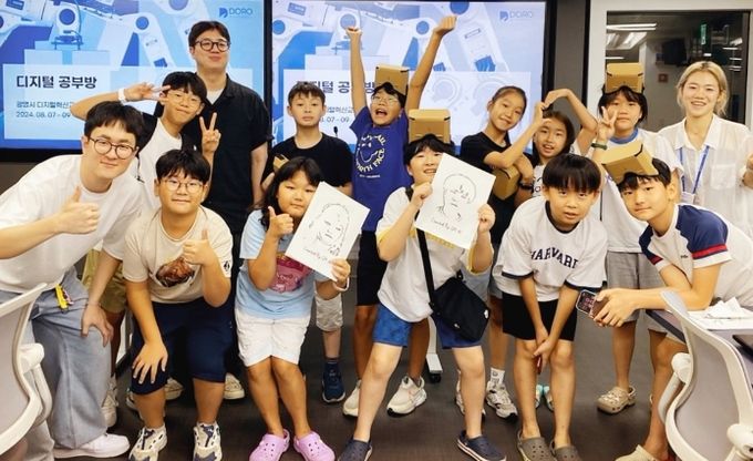 디지털 공부방에 참여한 대학생 멘토와 초등학생 멘티가 광명시디지털혁신교육센터에서 AI가 그린 초상화를 들고 기념사진을 촬영하고 있다