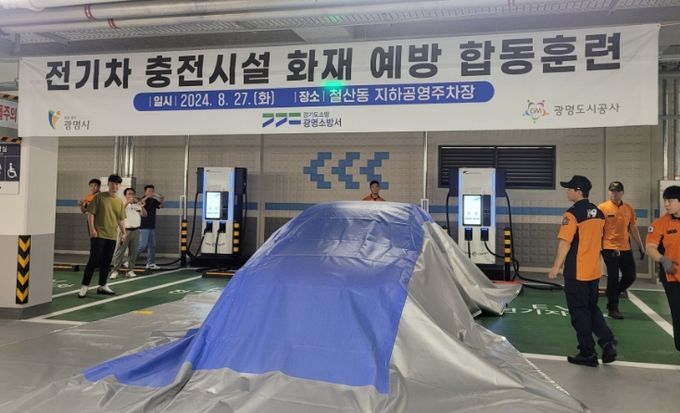 광명시는 지난 8월 27일 철산동 지하공영주차장에서 광명소방서와 '전기차 충전시설 화재 예방 합동훈련'을 실시했다. 사진은 질식소화포 사용법을 시연하는 모습