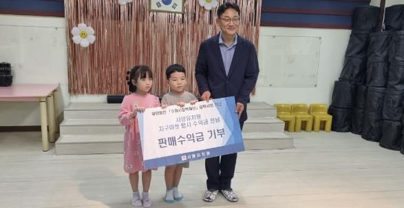 수원시 사랑유치원 풀잎반 유아들이 조승원 수원시 평생교육과장에게 기부금을 전달하고 기념사진을 촬영하고 있다.