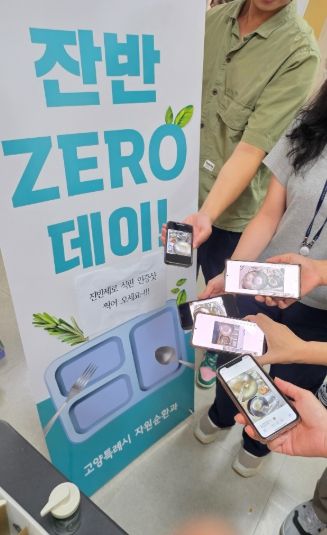 직원들이 잔반 없는 날(잔반 제로데이)’캠페인에서 잔반 없는 식판 인증샷을 꺼내보이고 있다.
